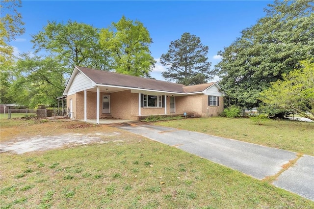 view of front of property with a carport, fence, brick siding, a front lawn, and driveway