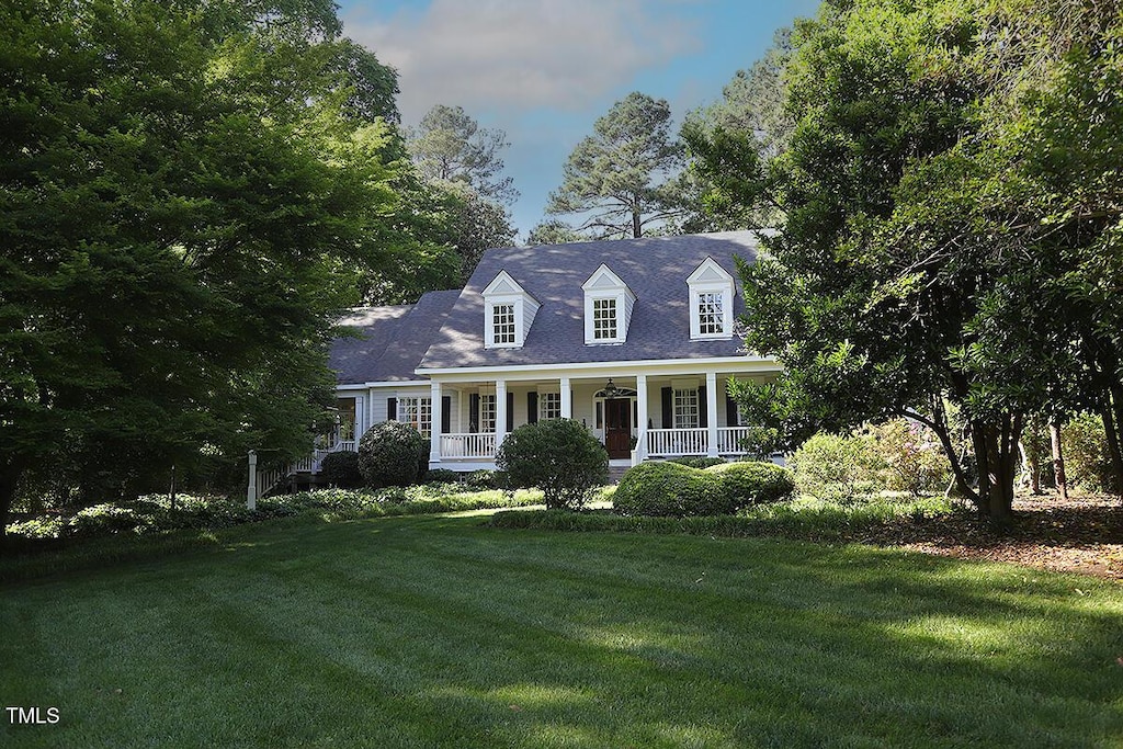 cape cod home featuring a porch and a front yard