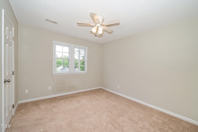 empty room featuring light colored carpet, visible vents, ceiling fan, and baseboards