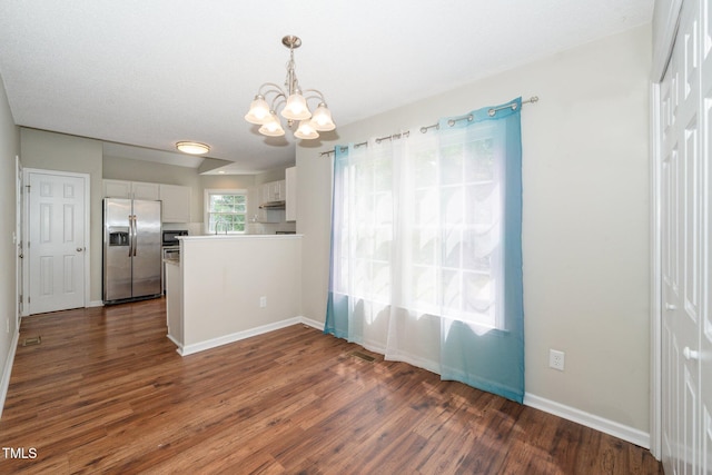unfurnished dining area with a chandelier, dark wood finished floors, and baseboards