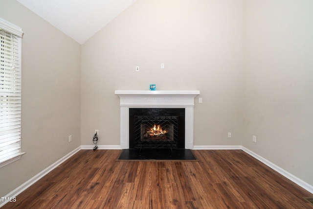 interior details with wood finished floors, a lit fireplace, and baseboards