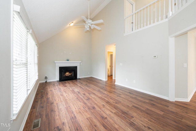 unfurnished living room with a fireplace with flush hearth, ceiling fan, visible vents, wood finished floors, and high vaulted ceiling