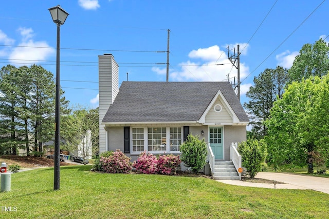 view of front facade featuring a front lawn, roof with shingles, and brick siding