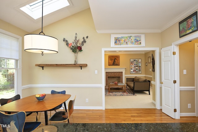 221 Ironwoods Dr, Chapel Hill, NC 27516 - dining area with wood finished floors, lofted ceiling with skylight, crown molding, baseboards, and a brick fireplace