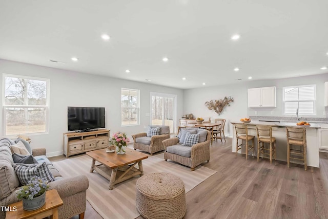 living room featuring baseboards, recessed lighting, and light wood-style floors