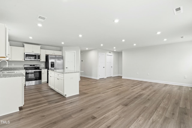 kitchen featuring a kitchen island, a sink, visible vents, and stainless steel appliances