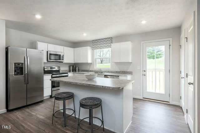 363 Tormore Dr, Sanford, NC 27330 - kitchen featuring dark wood-type flooring, appliances with stainless steel finishes, a kitchen island, and a breakfast bar