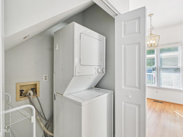 3303 Glen Currin Dr, Raleigh, NC 27612 - laundry area featuring stacked washing machine and dryer, a chandelier, and wood finished floors