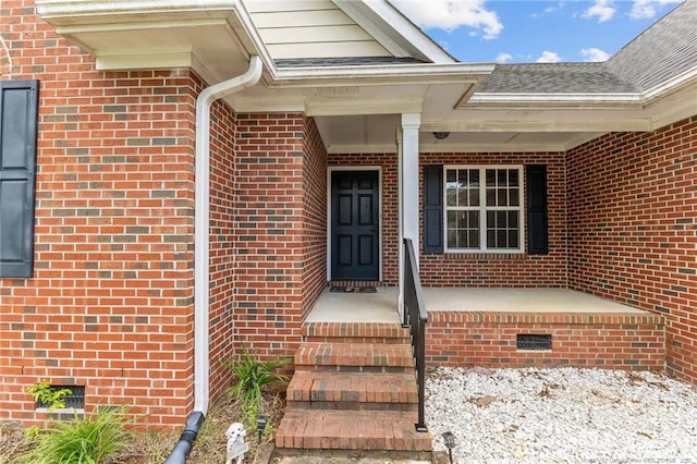 property entrance featuring crawl space, covered porch, and brick siding