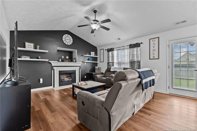 living room featuring visible vents, plenty of natural light, a ceiling fan, vaulted ceiling, and wood finished floors
