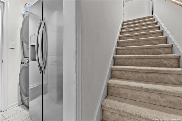 staircase featuring stacked washing maching and dryer, baseboards, and tile patterned flooring