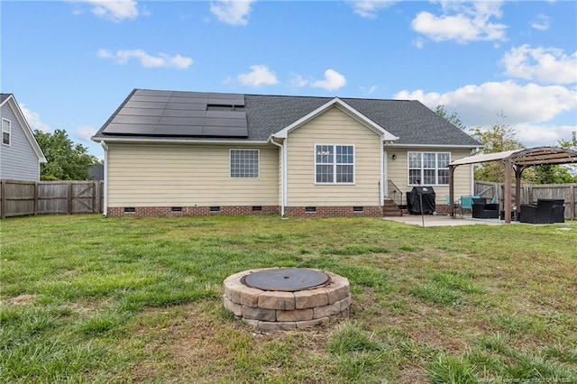 back of house with crawl space, a patio, an outdoor fire pit, and solar panels