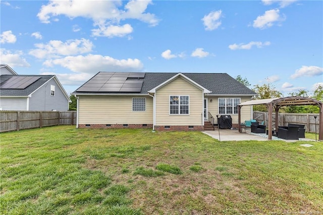 rear view of property featuring roof mounted solar panels, crawl space, a fenced backyard, a lawn, and a patio area