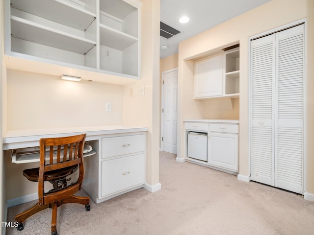 home office with light carpet, built in study area, and baseboards