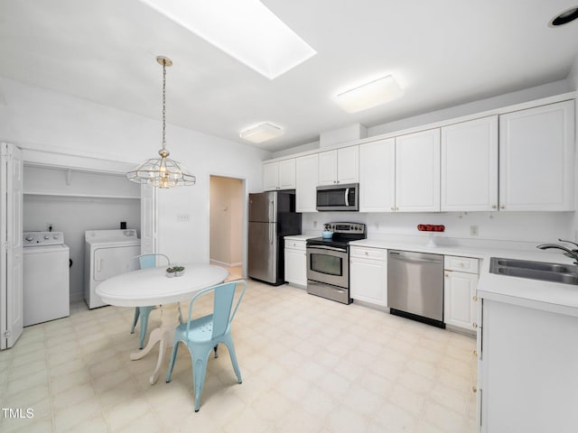 kitchen featuring stainless steel appliances, washer and dryer, a sink, light flooring, and a skylight