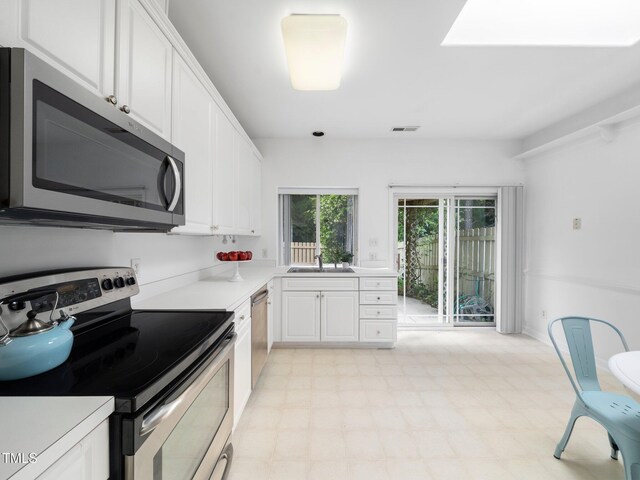 kitchen with stainless steel appliances, a sink, light countertops, and white cabinetry
