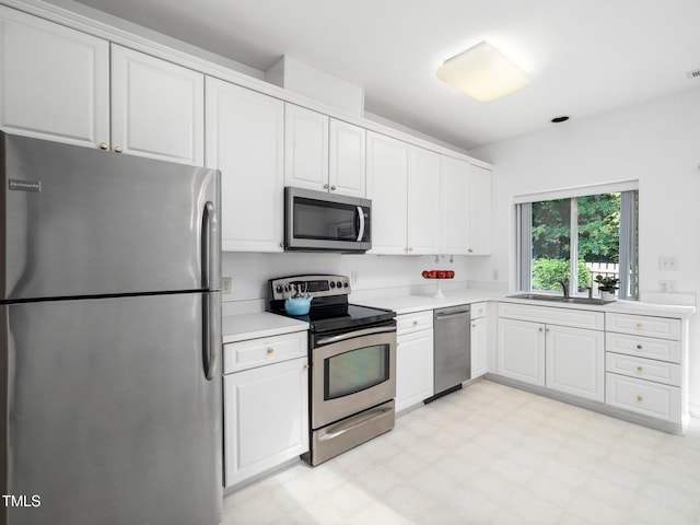 kitchen featuring appliances with stainless steel finishes, a sink, light countertops, and white cabinetry