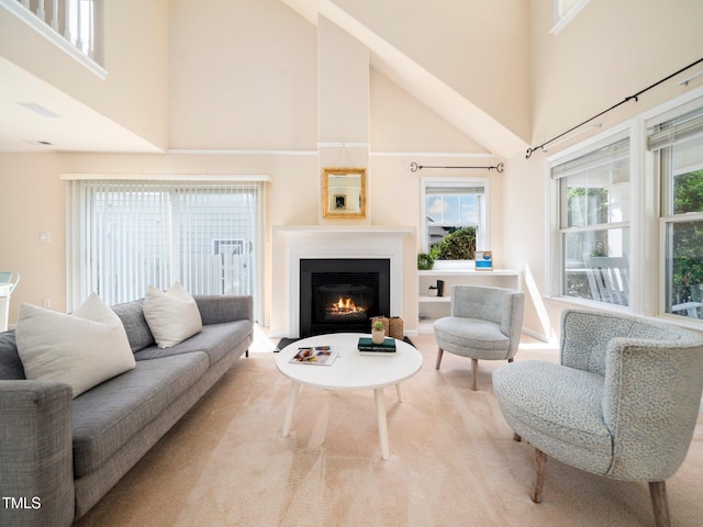 living room with a high ceiling and a lit fireplace