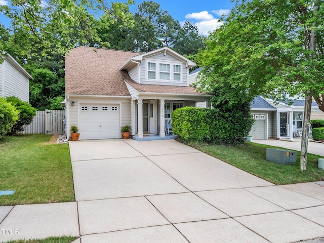 traditional home featuring an attached garage, driveway, a shingled roof, and covered porch