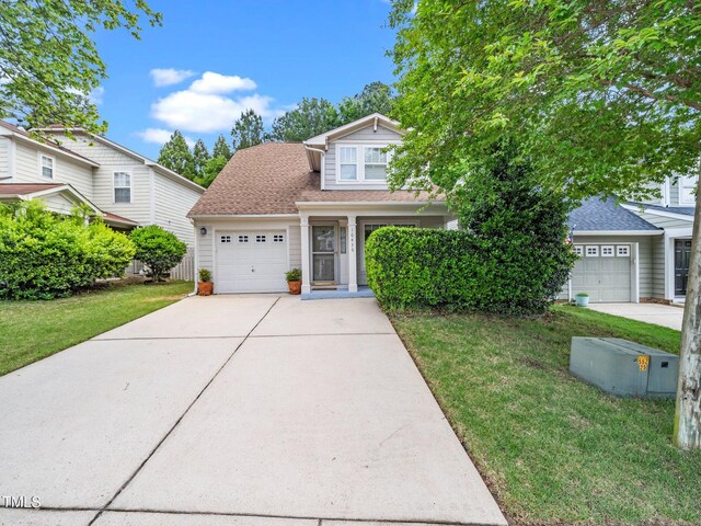 traditional-style home featuring concrete driveway, an attached garage, a front lawn, and roof with shingles