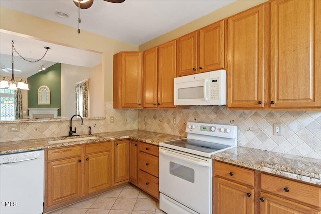 kitchen featuring a sink, white appliances, decorative backsplash, and light stone counters