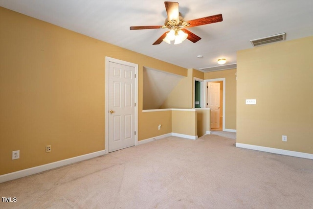 carpeted spare room with visible vents, baseboards, and ceiling fan
