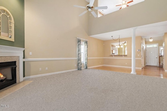 unfurnished living room featuring carpet floors, a high end fireplace, a ceiling fan, and baseboards