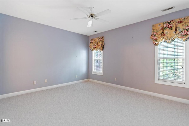carpeted spare room with ceiling fan, baseboards, and visible vents