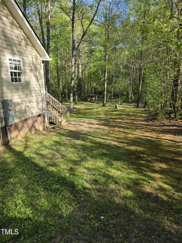 view of grassy yard featuring a view of trees