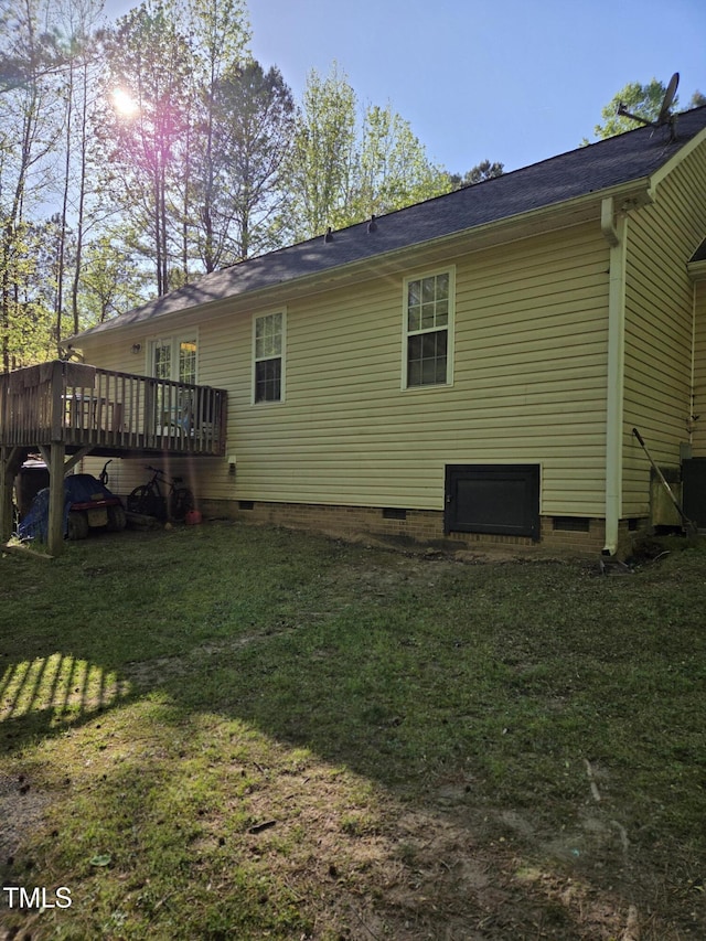 rear view of house with crawl space, a wooden deck, and a yard
