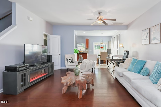 living area with wood finished floors, visible vents, and a ceiling fan