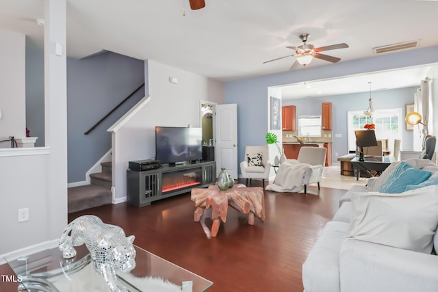 living room featuring stairway, wood finished floors, ceiling fan, baseboards, and visible vents