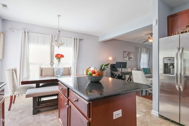 kitchen featuring a center island, dark stone countertops, visible vents, ceiling fan, and stainless steel refrigerator with ice dispenser