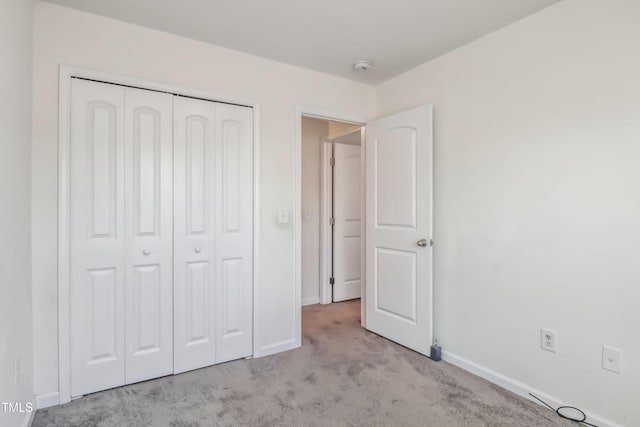 unfurnished bedroom featuring carpet floors, a closet, and baseboards