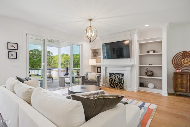 143 Sallyport Ct, Raleigh, NC 27603 - living area featuring light wood-style floors, built in features, an inviting chandelier, a fireplace, and recessed lighting