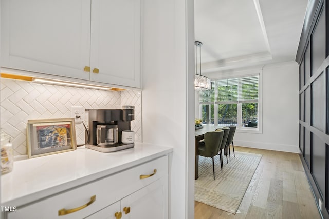 143 Sallyport Ct, Raleigh, NC 27603 - kitchen featuring a tray ceiling, light wood-style flooring, light countertops, and backsplash