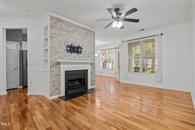 8231 Allyns Landing Way Unit 101, Raleigh, NC 27615 - unfurnished living room featuring ornamental molding, ceiling fan, light wood-style floors, a stone fireplace, and built in shelves