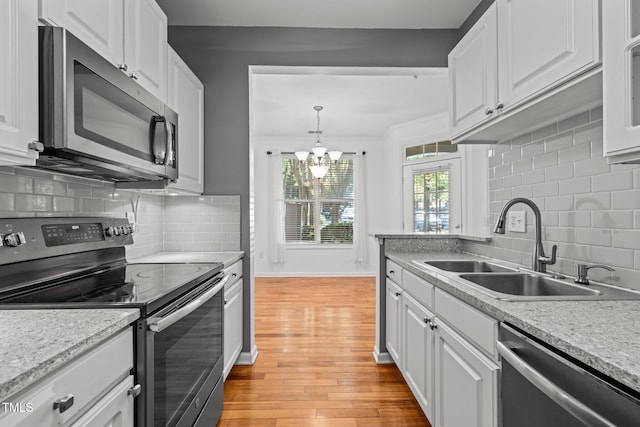 8231 Allyns Landing Way Unit 101, Raleigh, NC 27615 - kitchen featuring appliances with stainless steel finishes, white cabinetry, light wood-type flooring, tasteful backsplash, and a chandelier