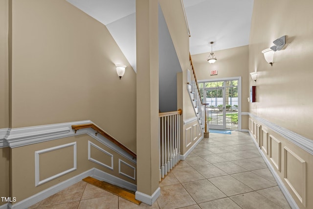 8231 Allyns Landing Way Unit 101, Raleigh, NC 27615 - hallway featuring light tile patterned floors, a decorative wall, an upstairs landing, and a wainscoted wall