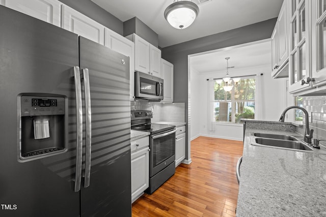 8231 Allyns Landing Way Unit 101, Raleigh, NC 27615 - kitchen featuring appliances with stainless steel finishes, decorative backsplash, light wood-type flooring, white cabinets, and glass insert cabinets