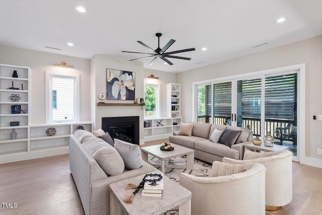 337 Merrywood Dr, Raleigh, NC 27610 - living area featuring light wood finished floors, a glass covered fireplace, built in features, and ceiling fan