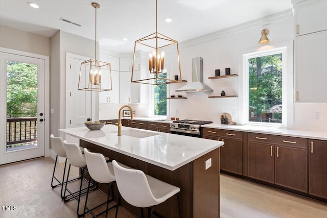 337 Merrywood Dr, Raleigh, NC 27610 - kitchen with light wood finished floors, a sink, wall chimney exhaust hood, gas range, and a notable chandelier