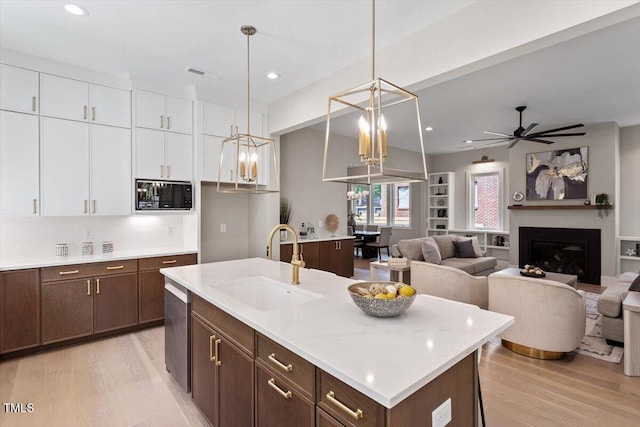 337 Merrywood Dr, Raleigh, NC 27610 - kitchen featuring black microwave, white cabinetry, a sink, and light wood finished floors
