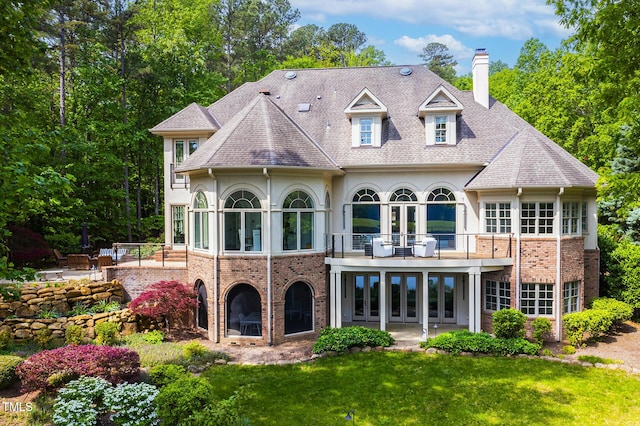 back of house with a chimney, a balcony, a yard, a patio area, and french doors