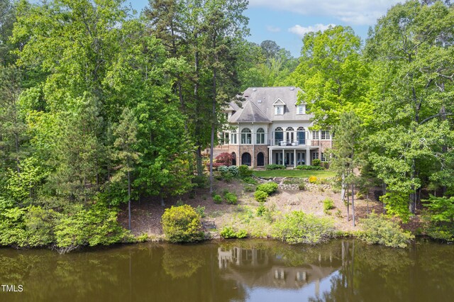 back of house featuring a balcony, brick siding, and a water view