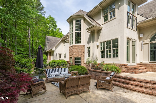 back of house with a patio area, outdoor lounge area, roof with shingles, and stucco siding