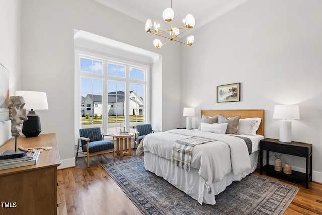 bedroom with a chandelier, wood finished floors, and baseboards