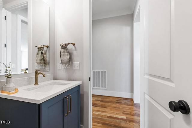 bathroom featuring baseboards, vanity, wood finished floors, and visible vents