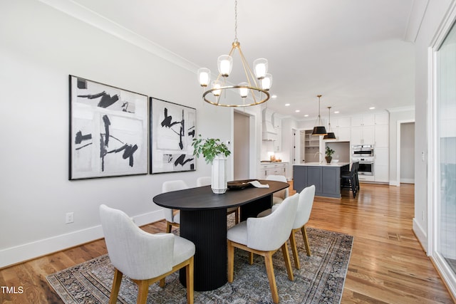 dining space with baseboards, crown molding, a chandelier, and light wood-type flooring