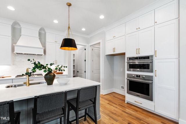 kitchen with white cabinets, decorative light fixtures, a kitchen breakfast bar, and custom exhaust hood